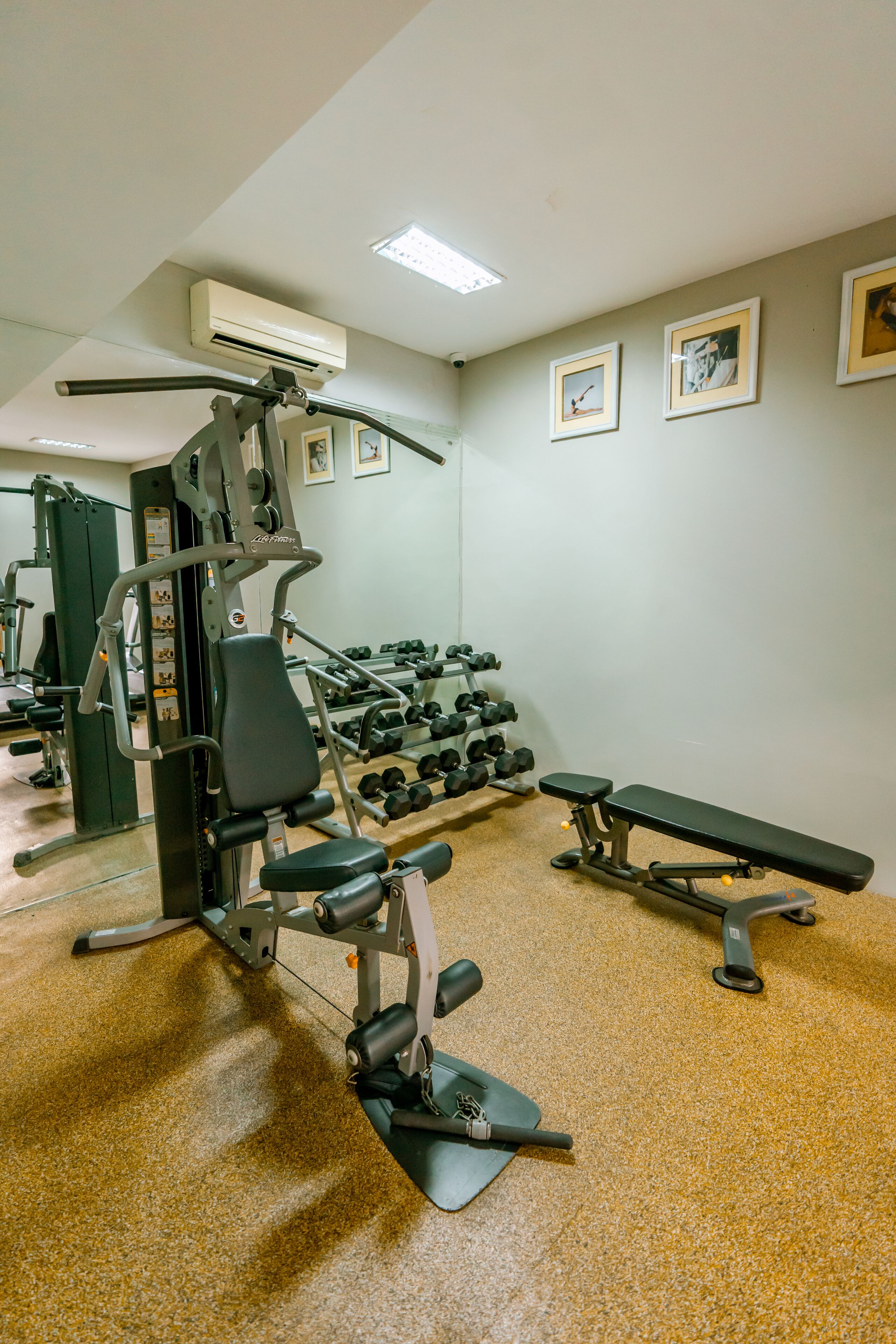 A gym with exercise equipment, dumbbells, and benches.