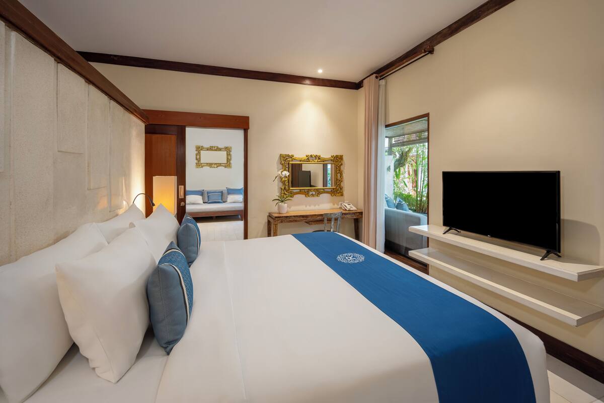 A hotel room with a bed, a television, a desk, and a mirror.