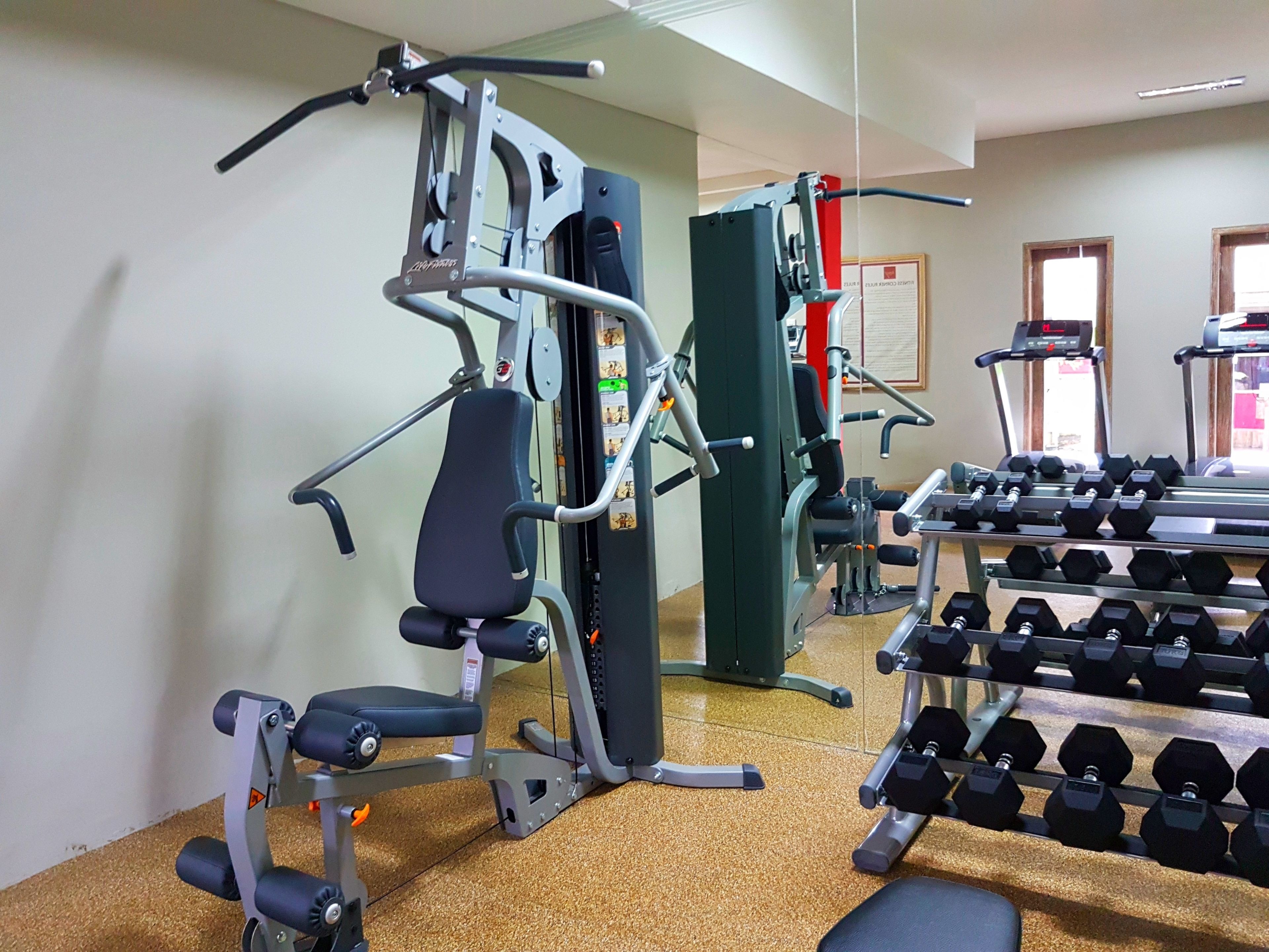A gym with exercise equipment, dumbbells, and treadmills.