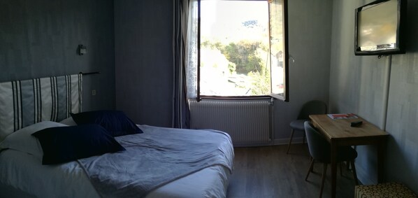 Un dormitorio con una cama, una ventana, un escritorio y una silla.
