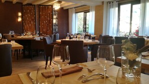 Un restaurante con varias mesas, sillas y copas de vino.