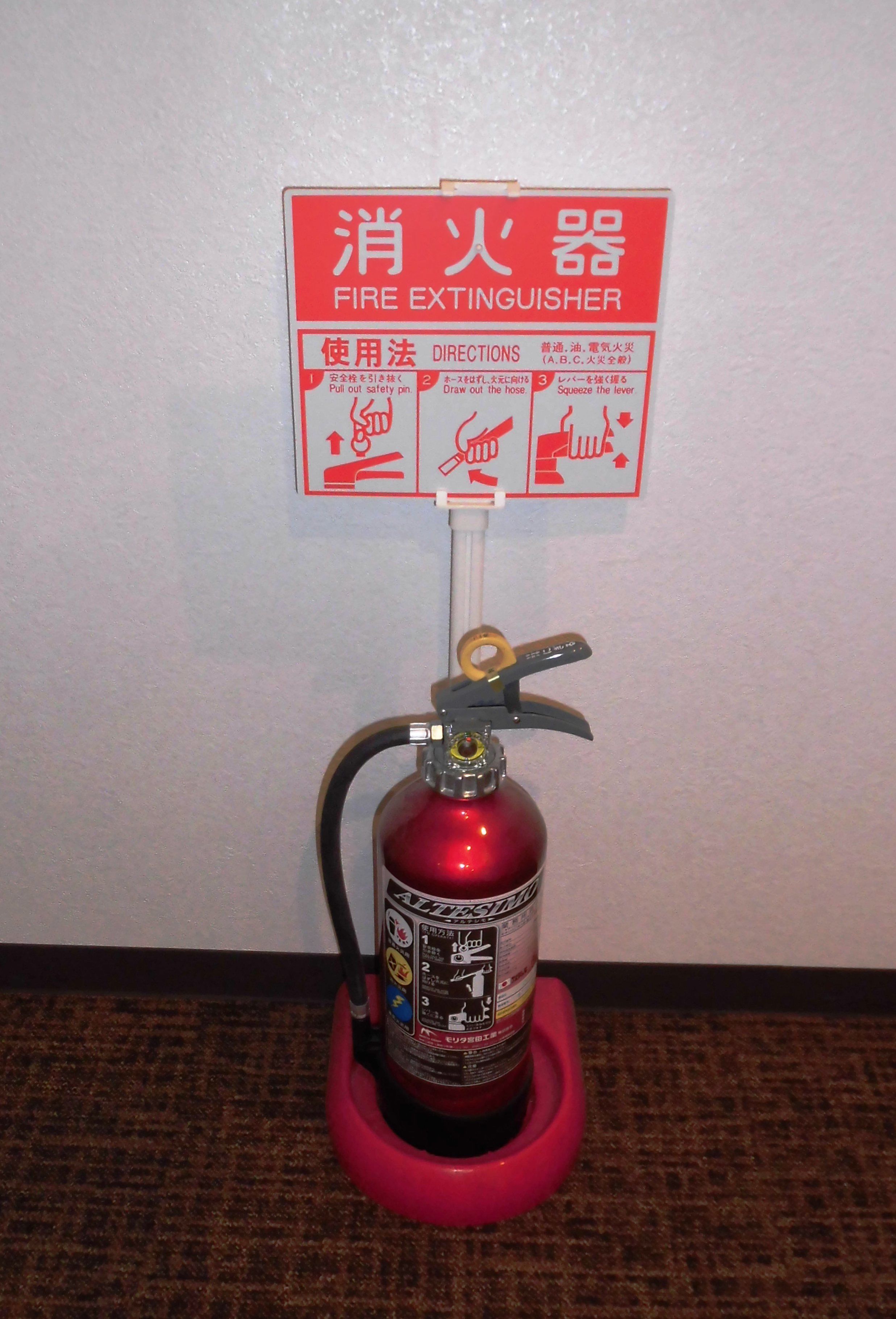 A fire extinguisher mounted on a wall with a red base and a red label.