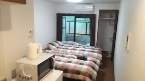 A small hotel room with a bed, a microwave, a kettle, and a sliding door to the outside. - KyotoHouseToji (Kyoto)