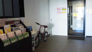A reception area with a ticket counter, a bicycle, and a door with signage. - KyotoHouseToji (Kyoto)