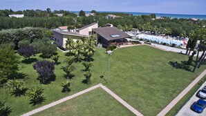 An aerial view of a resort with a large grassy area, a pool, and several buildings.