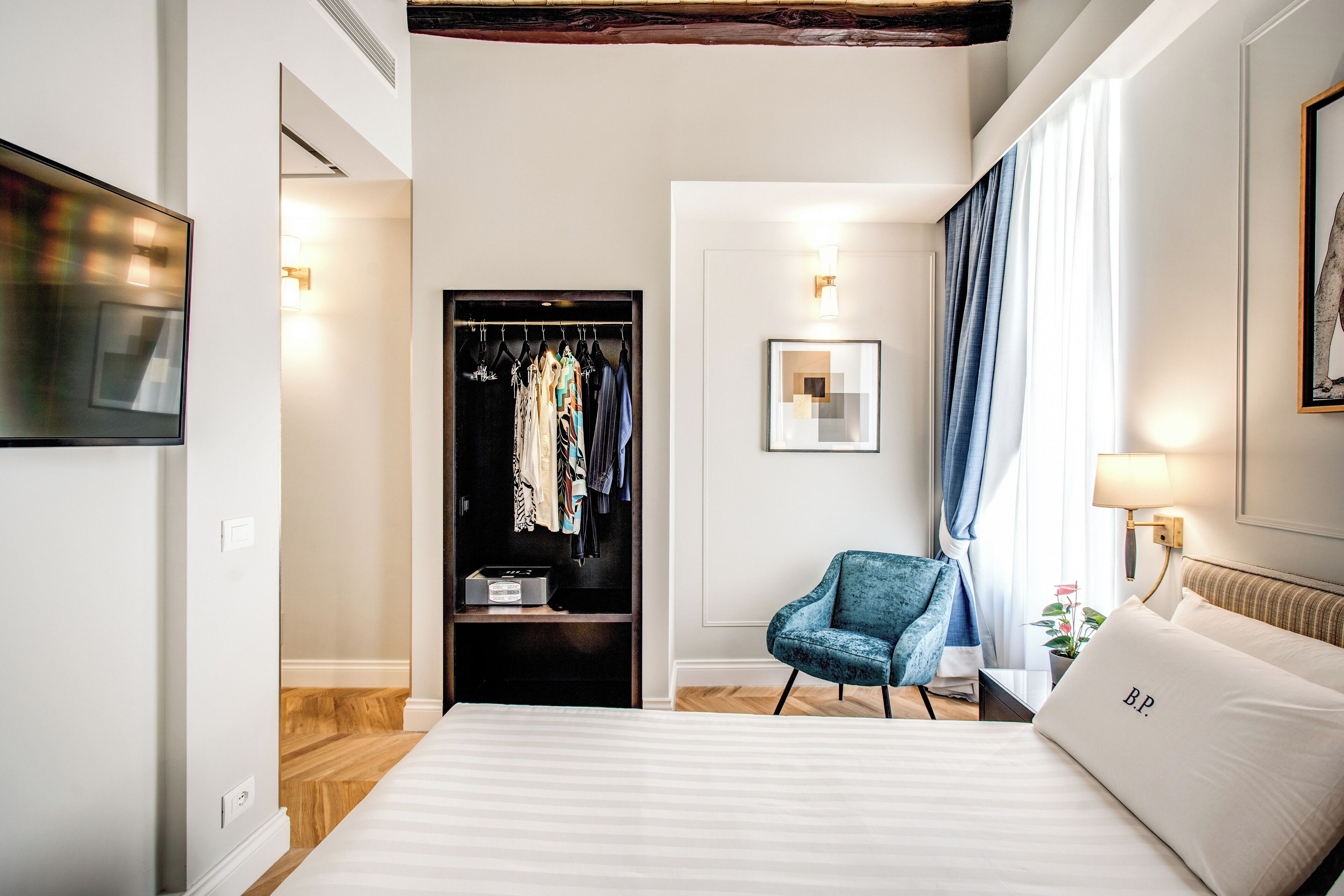 Una habitación de hotel con una cama grande, un armario, una silla y un televisor.