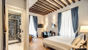 Una habitación de hotel con cama, escritorio, silla, televisión y baño con ducha.
