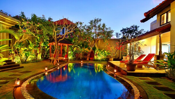 A swimming pool surrounded by a garden with plants and a gazebo.