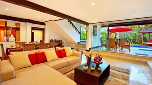 A modern living room with a sofa, coffee table, and a dining area with chairs and a table.