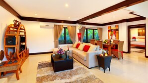A spacious living room with a white sofa, a black coffee table, and a wooden entertainment unit.