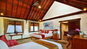 A spacious bedroom with two beds, a desk, and a large window.