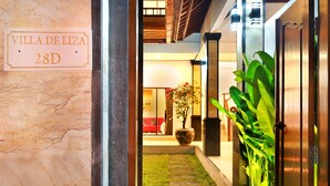 A hallway with a sign reading "Villa De Liza 28D", a potted plant, a door, and a stone pathway. - Villa De Liza Seminyak Beachside (Seminyak)
