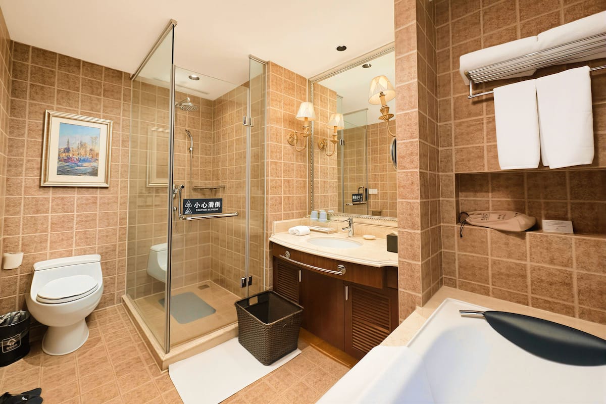 A modern bathroom with a glass-enclosed shower, a sink, a bathtub, and a toilet.