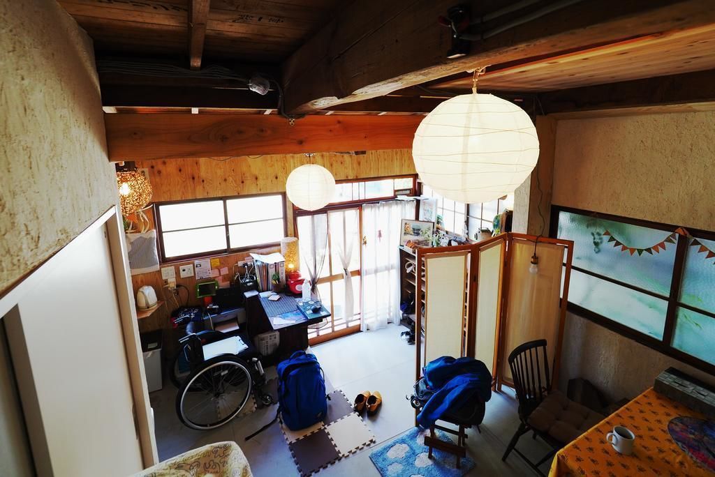 A traditional Japanese room with tatami flooring, a wheelchair, a desk with a computer, and a sliding door leading to another room.