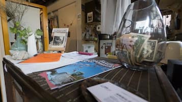 A cluttered desk with a glass vase containing money, a framed picture, and various papers.