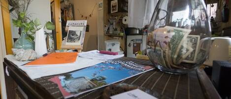 A cluttered desk with a glass vase containing money, a framed picture, and various papers.