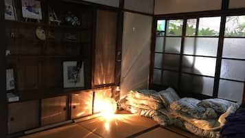 Ein traditioneller japanischer Raum mit Tatami-Bodenbelag, einem Futon, einem Shoji-Bildschirm und einem Holzboden mit diversen Gegenständen.