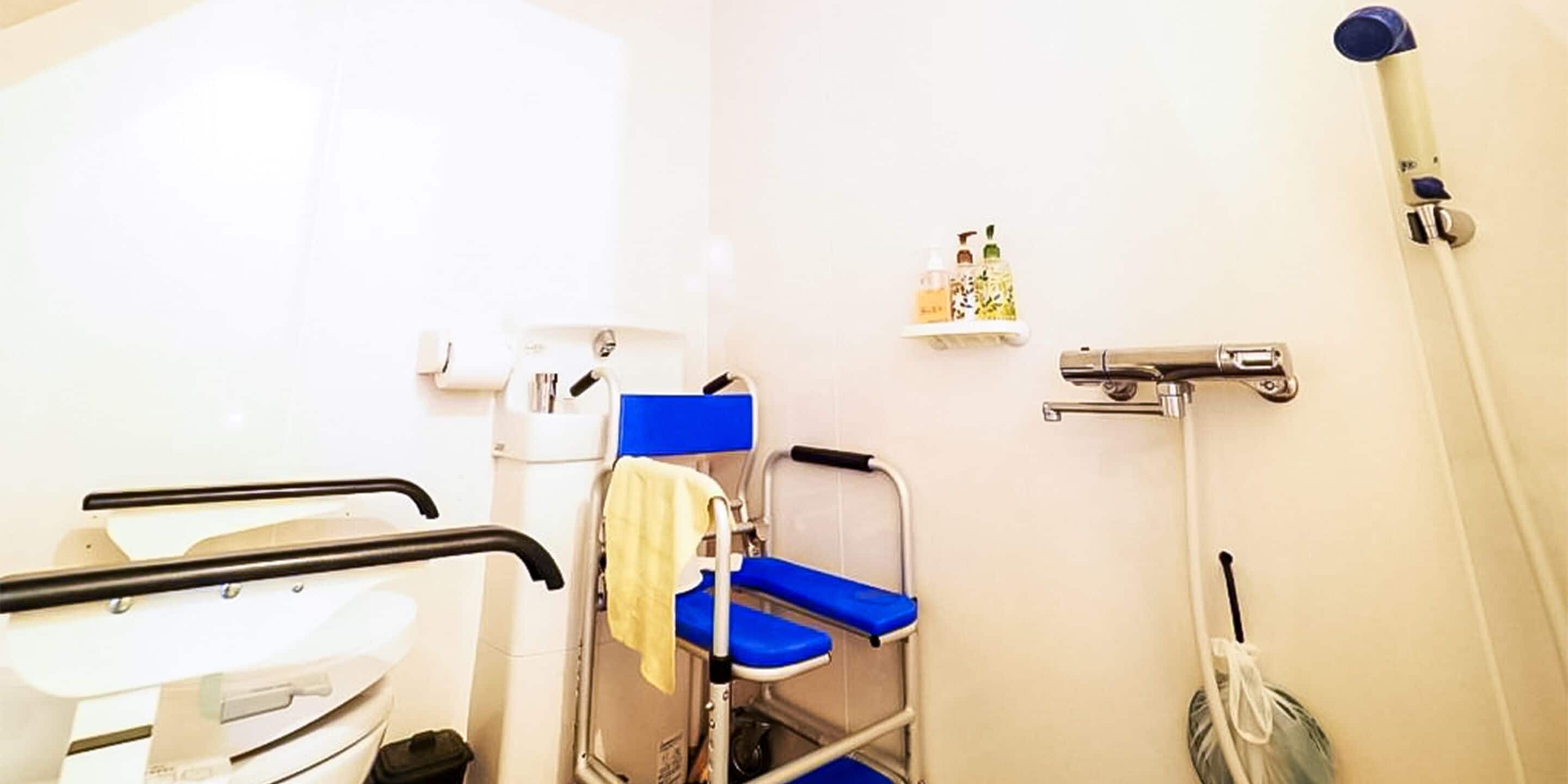 A bathroom with a wheelchair, a shower, and a shelf with toiletries.