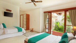 A hotel room with two beds, a TV, a ceiling fan, and a view of a garden through a sliding door. - Lucia Villa Seminyak (Seminyak)