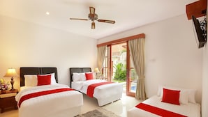 A hotel room with two beds, a ceiling fan, a view of the outdoors, and a small table with a lamp. - Lucia Villa Seminyak (Seminyak)