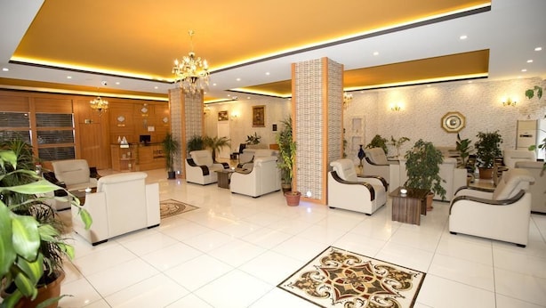 Un hall amplio con varias zonas de estar, un candelabro y plantas decorativas.