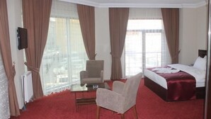 Una habitación de hotel con cama, una silla, una mesita y televisión.