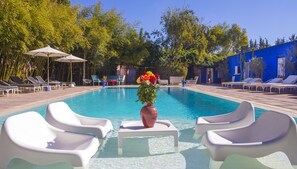 Una piscina al aire libre, sombrillas, sillones reclinables de piscina