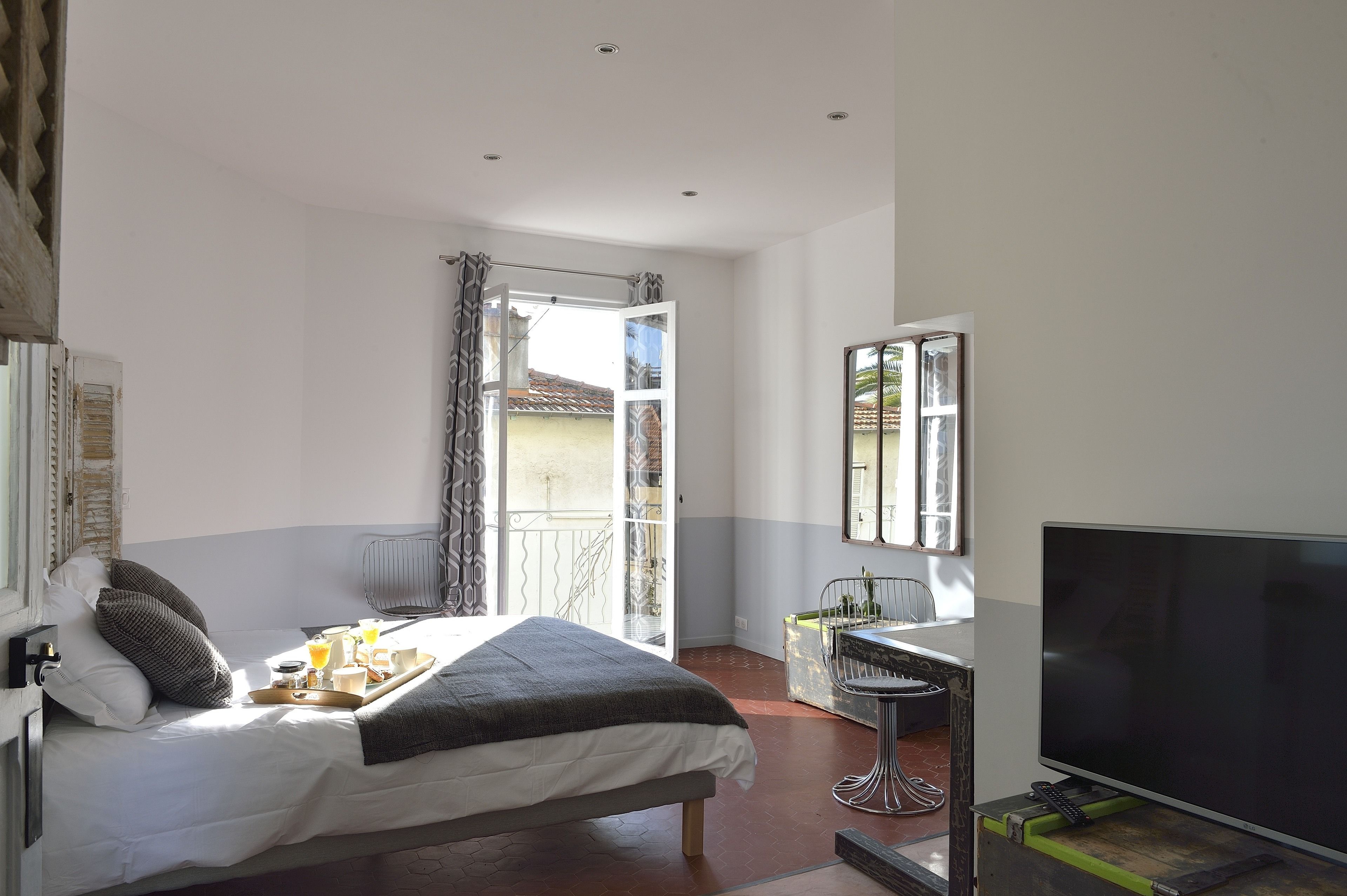 Een slaapkamer met een bed, een ontbijttafel, televisie en een balkon met uitzicht.