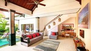 A spacious living area with a sofa, a desk, and a staircase. - Concetta Villa Seminyak Beachside (Seminyak)