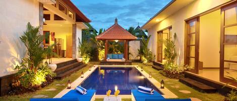 Piscina com espreguiçadeiras, um gazebo e um jardim bem cuidado.