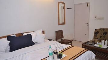 A hotel room with a bed, a chair, a small table with a tray of toiletries, and a door.
