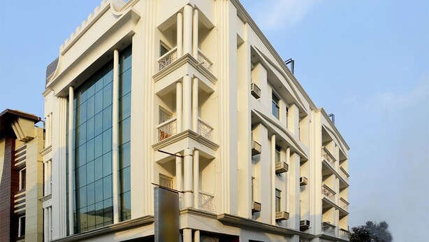 Um edifício moderno com fachada de vidro extensa, várias varandas e design arquitetônico simétrico.