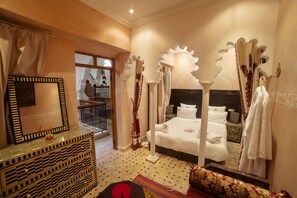 A bedroom with a four-poster bed, a large mirror, and a decorative headboard. - Dar Ikalimo Marrakech (Marrakech)