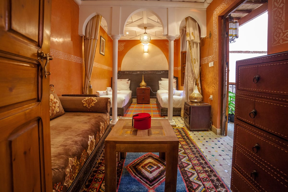A traditional room with a sofa, a table, and a bed with white linens.