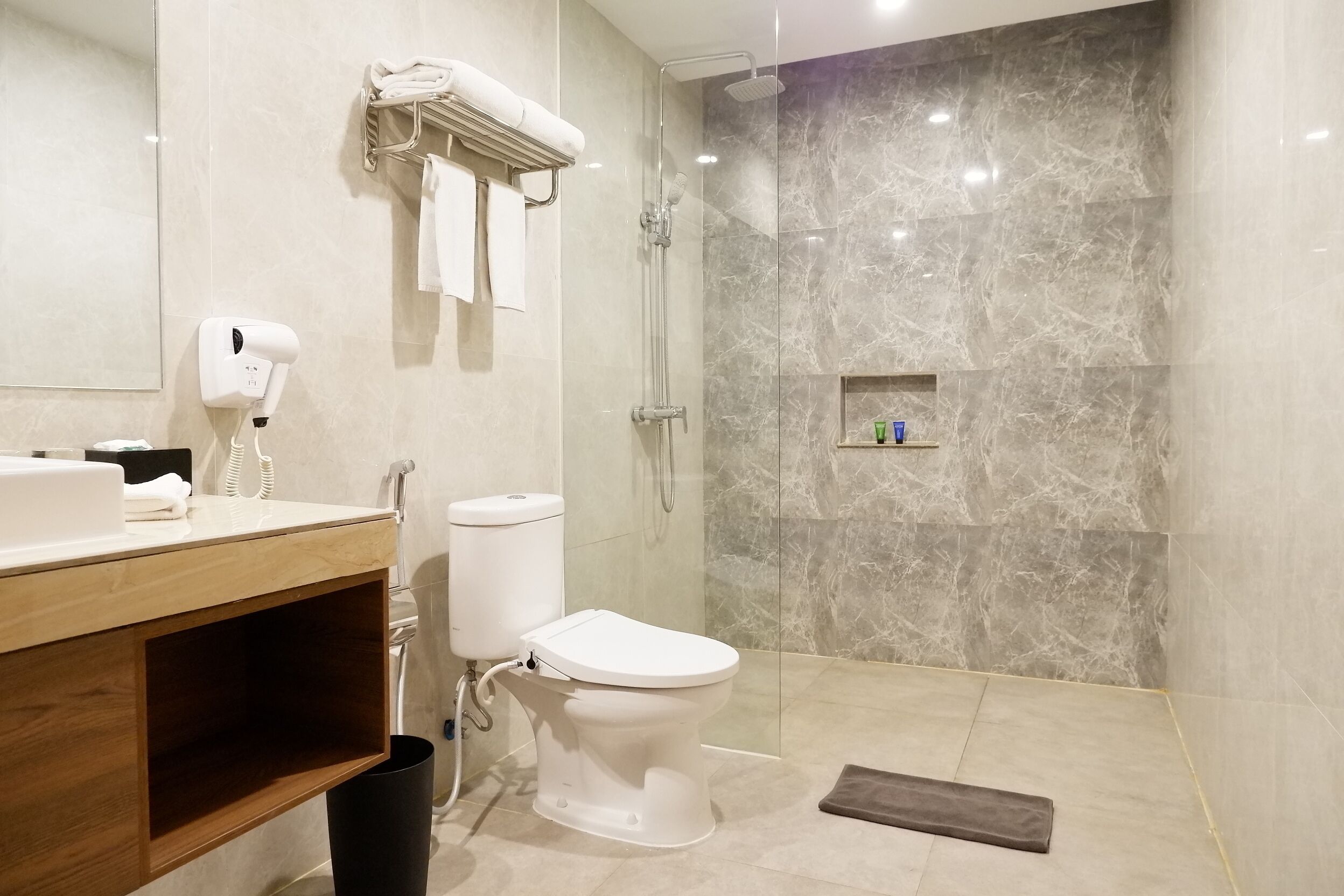 Un baño moderno con inodoro, ducha, secador de pelo y toallero.