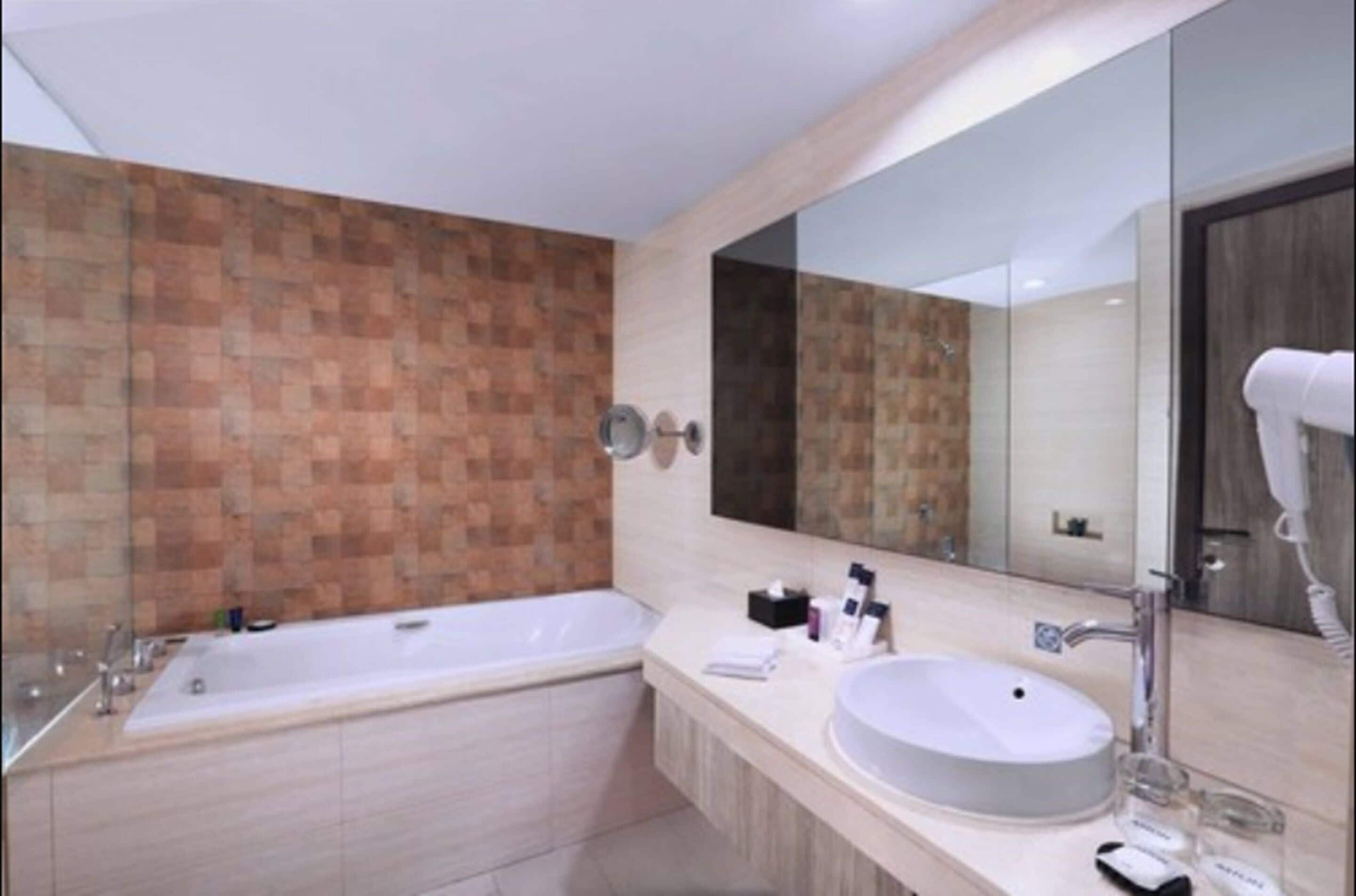 A modern bathroom with a large bathtub, a round sink, and a mirror.