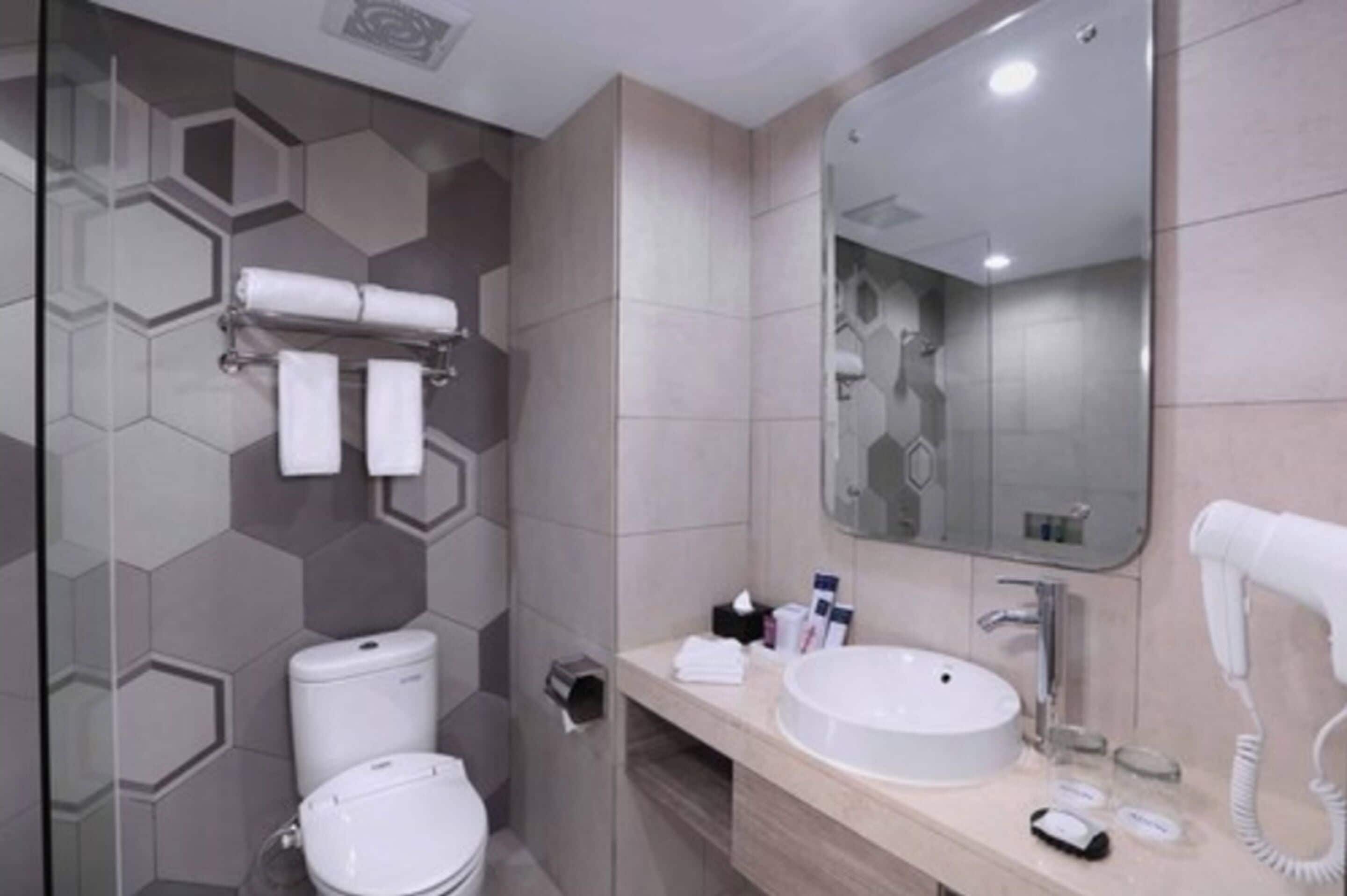 A modern bathroom with a toilet, sink, and a hairdryer on the counter.
