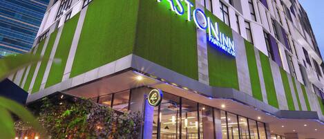 A multi-story hotel with a prominent green and white facade, large windows, and a visible entrance.