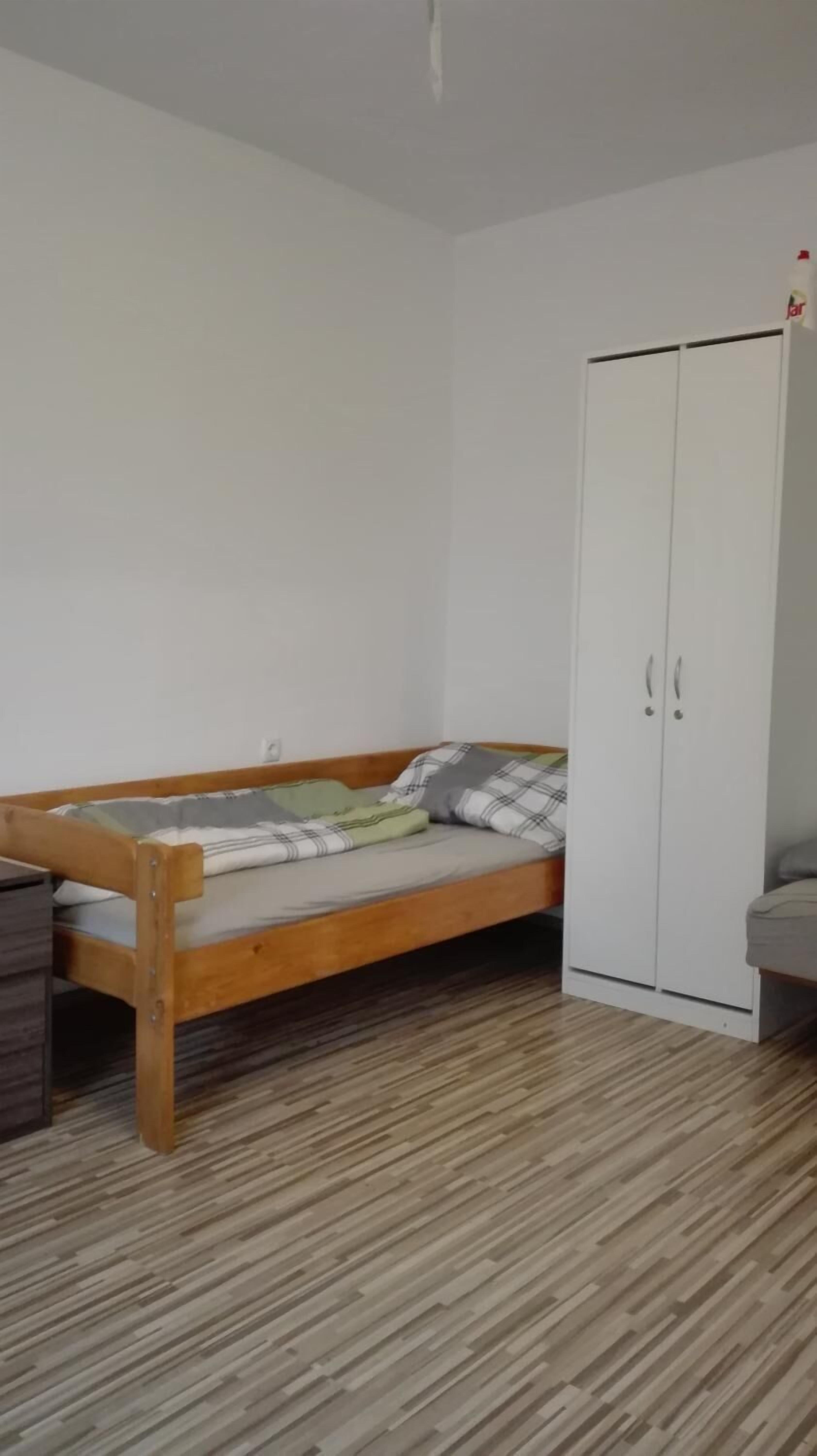 Una habitación con una cama de madera, un armario y piso de madera.