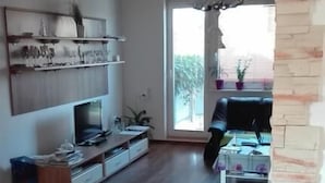 Un salón espacioso con suelo de madera, televisor de pantalla plana y chimenea.
