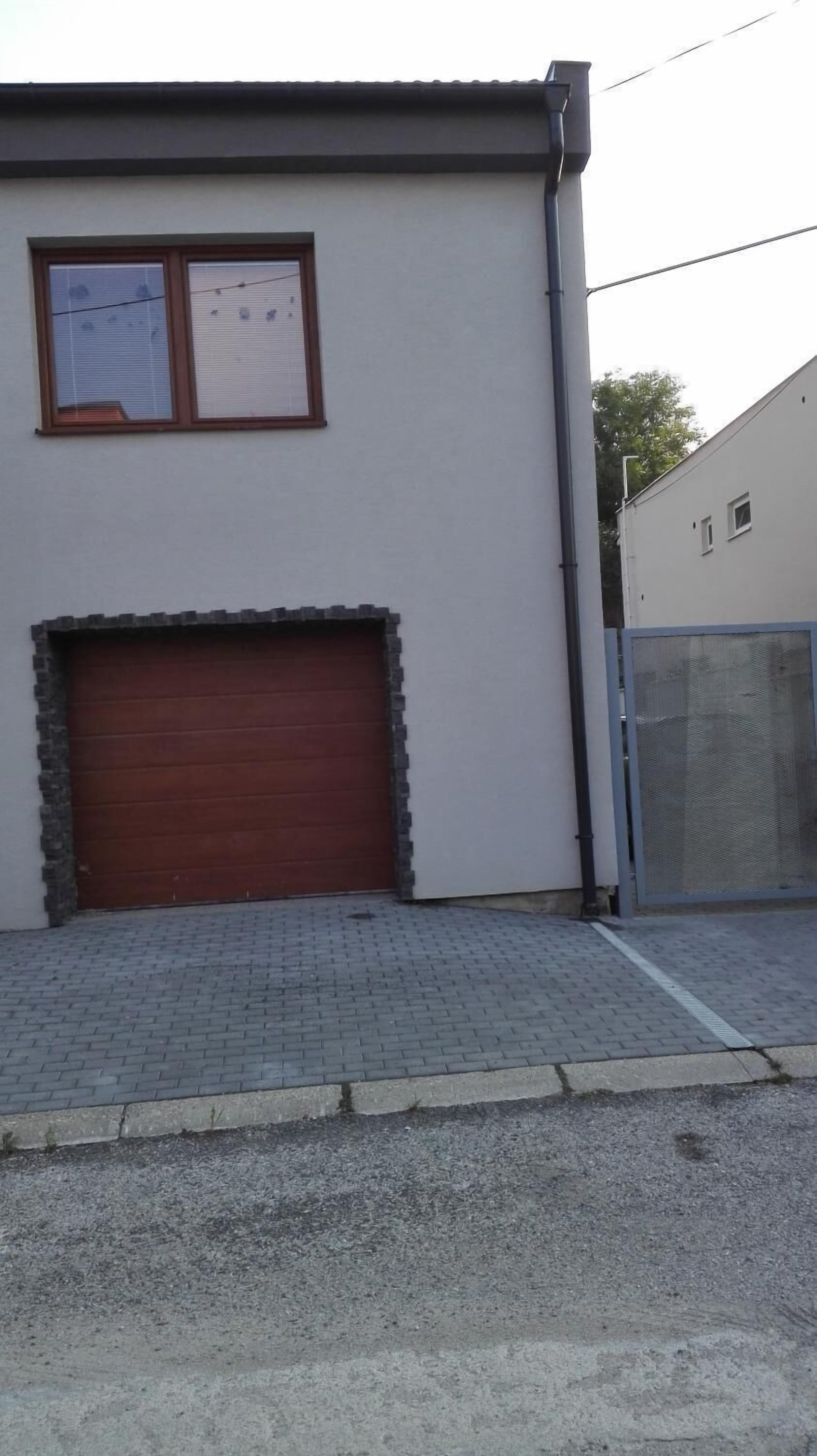 A building with a closed garage door, a paved entrance area, and a metal fence.