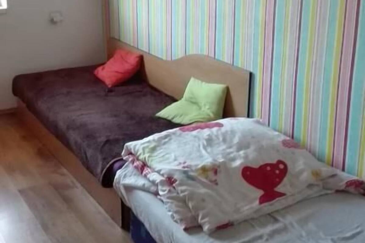 A bedroom with two beds, striped wallpaper, and a wooden floor.