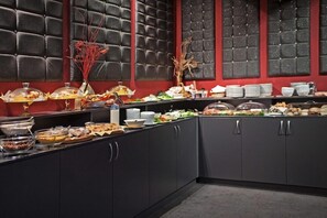 A buffet setup with various food items and a decorative wall with a red and black color scheme. - Akord Business Hotel (Sofia)