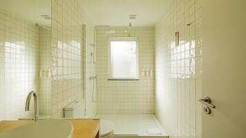 A bathroom with a bathtub, toilet, shower, and a window providing natural light.