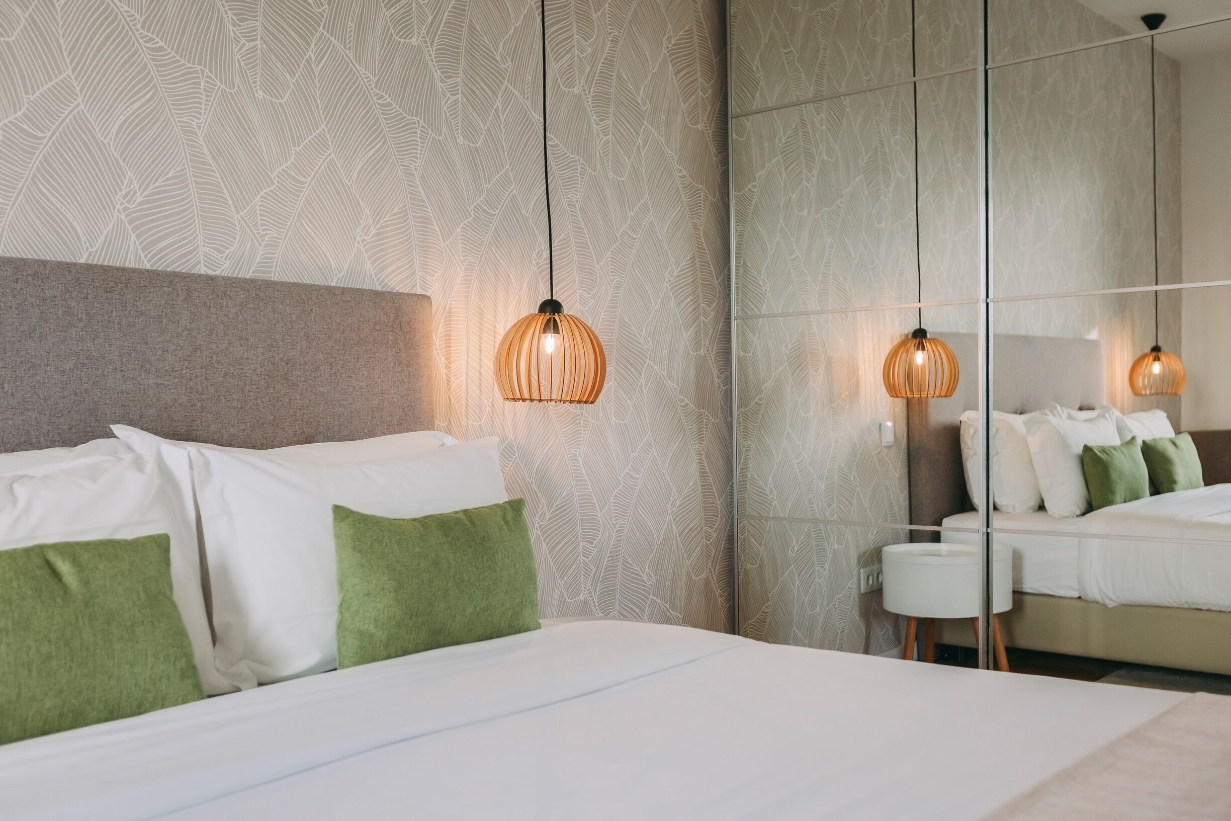 A modern hotel room with a large bed, green pillows, and a textured wall.
