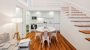 A modern interior with a dining area, kitchen, and staircase.