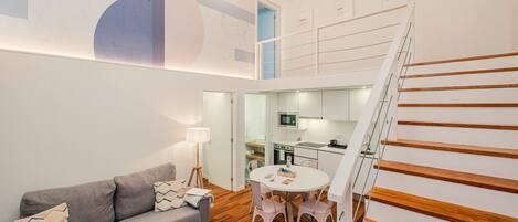 A modern living room with a grey sofa, a round table, and a staircase with wooden steps.