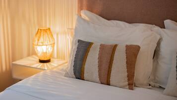 A neatly made bed with striped pillows and a bedside lamp.