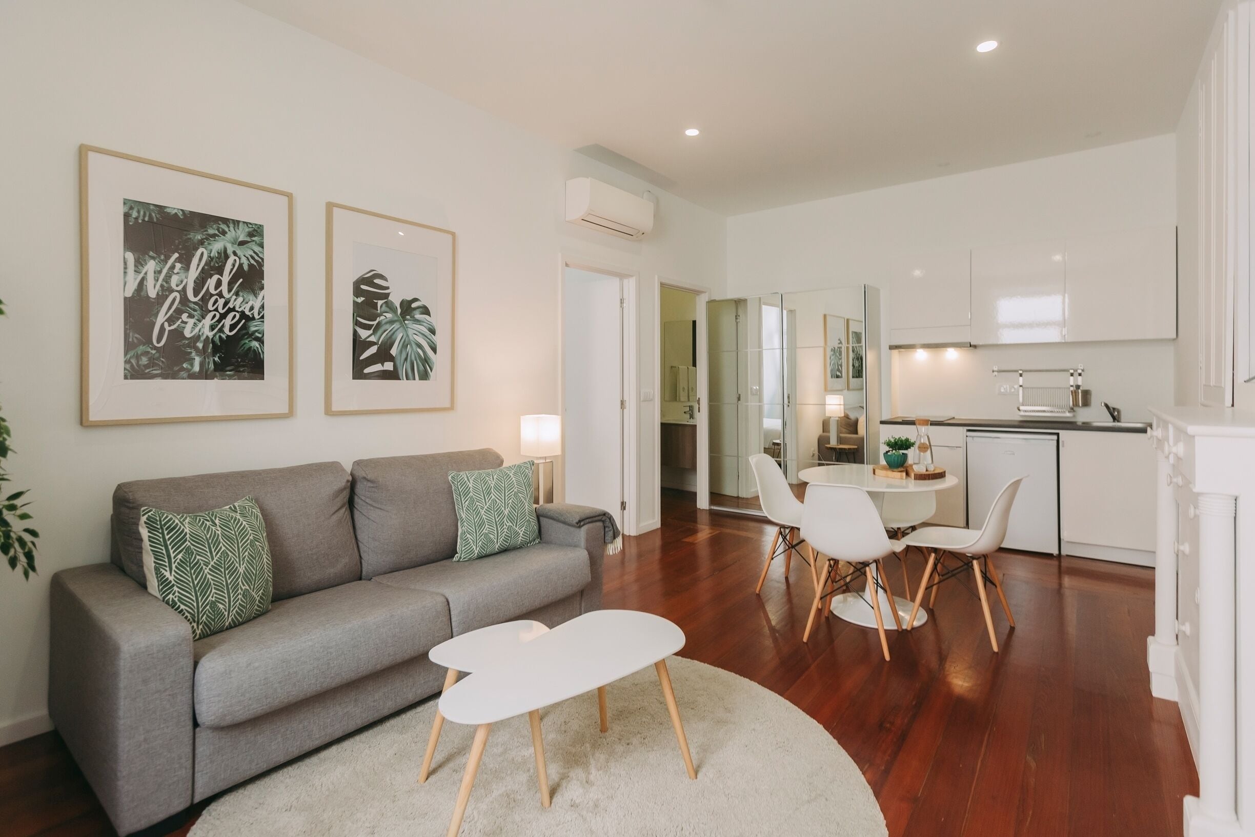 A modern living room with a grey sofa, white coffee table, and framed artwork on the wall.