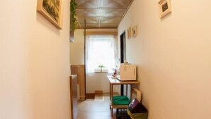 A narrow hallway with wooden flooring, a ceiling light, and framed pictures on the walls. - Penzion Mona (Bela pod Pradedem)